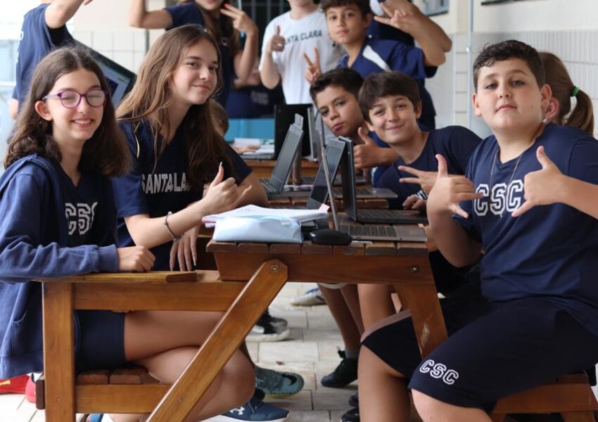 Foto mostra alunos estudando em grupo fora da sala de aula.